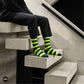Bold Stripes Neon Green and Olive crew socks worn on modern concrete staircase with black trousers — Dynamocks