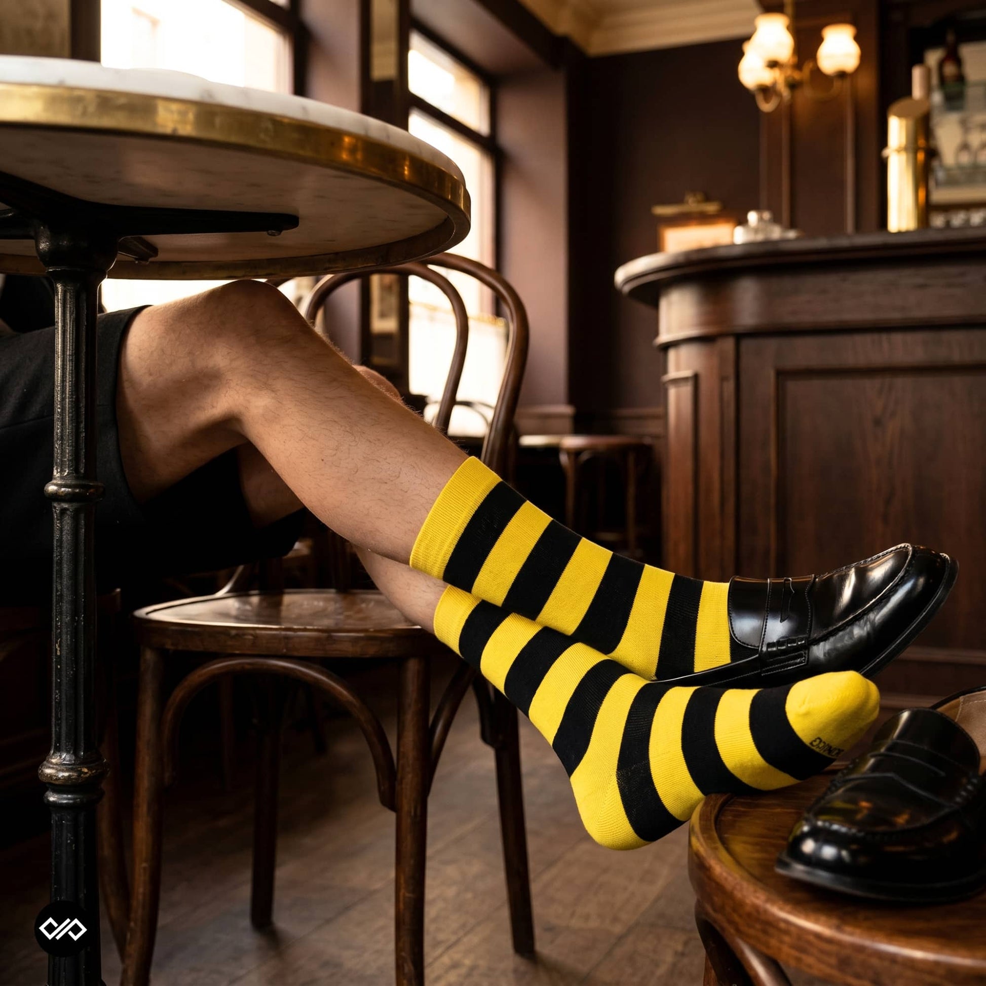 Bold yellow and black striped crew socks styled in a café with black loafers — Dynamocks