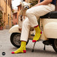 Chillies crew socks styled with cream trousers seated on a vintage scooter on a cobbled street – Dynamocks