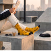 Cutting Chai Indian crew socks for men styled with rooftop chai and newspaper — marigold yellow design — Dynamocks