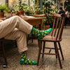 Fresh leaf crew socks styled with cream linen trousers at a plant-filled café table — Dynamocks