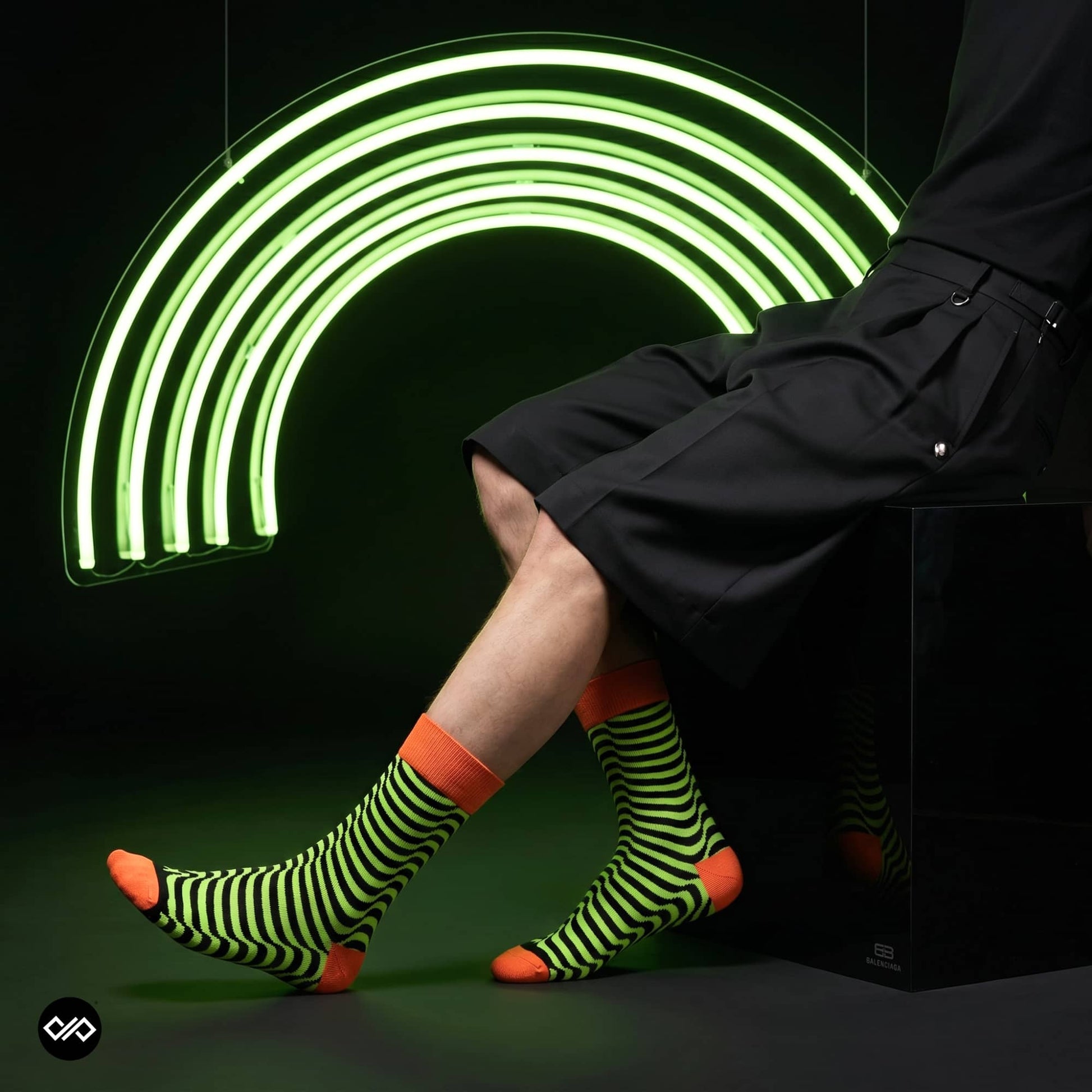 Illusion neon striped crew socks styled with black tailored shorts under a green neon arc — Dynamocks India