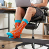 Origami paper plane crew socks worn at a home office workspace with grey shorts and ergonomic chair — Dynamocks