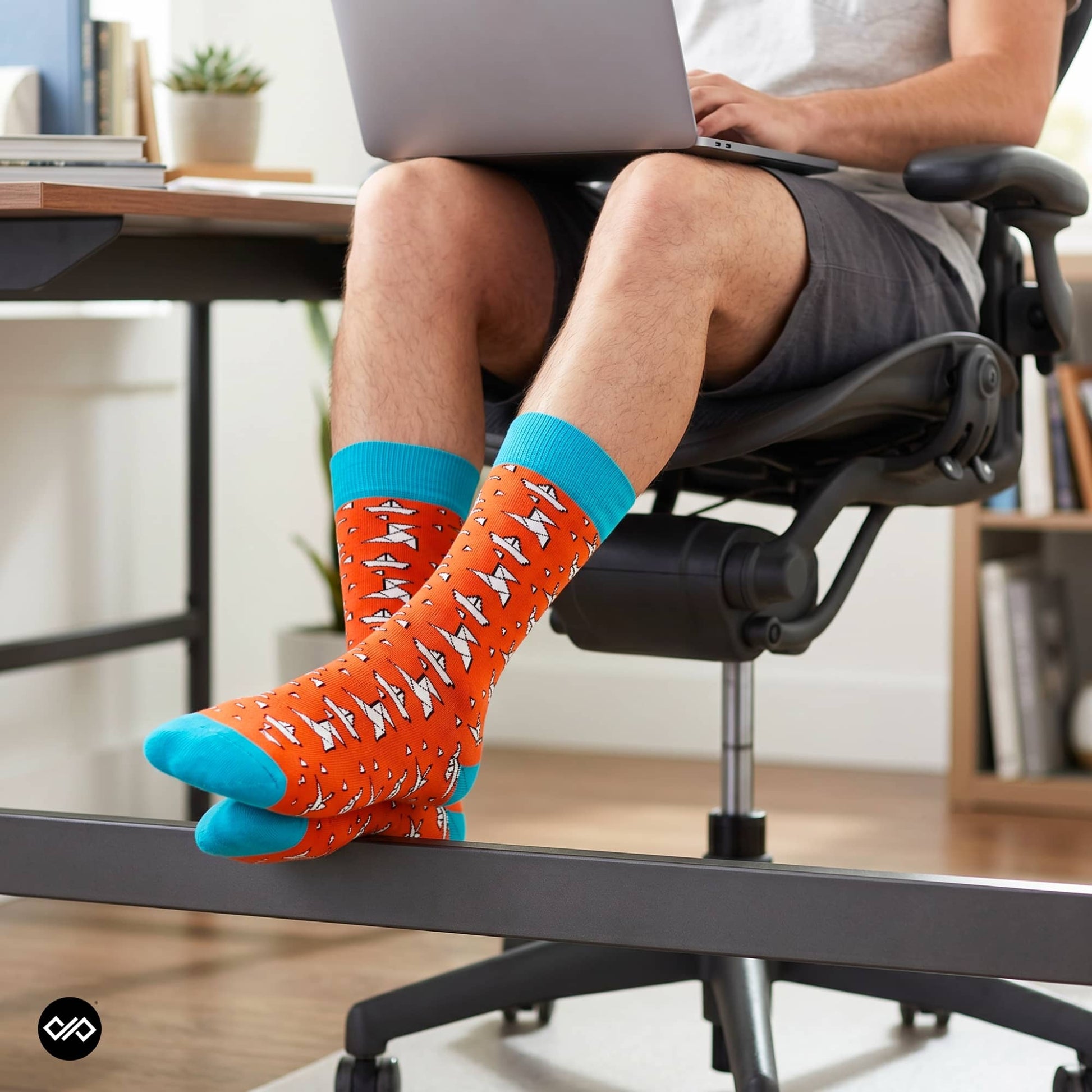 Origami paper plane crew socks worn at a home office workspace with grey shorts and ergonomic chair — Dynamocks