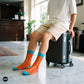 Origami orange and aqua paper plane crew socks styled with beige shorts in a hotel lobby — Dynamocks