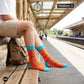 Origami paper plane crew socks at a train station platform with khaki shorts and travel backpack — Dynamocks