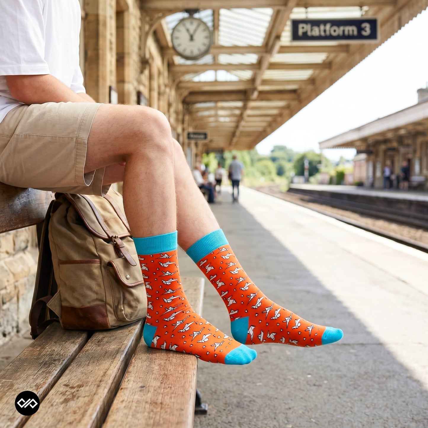 Origami paper plane crew socks at a train station platform with khaki shorts and travel backpack — Dynamocks