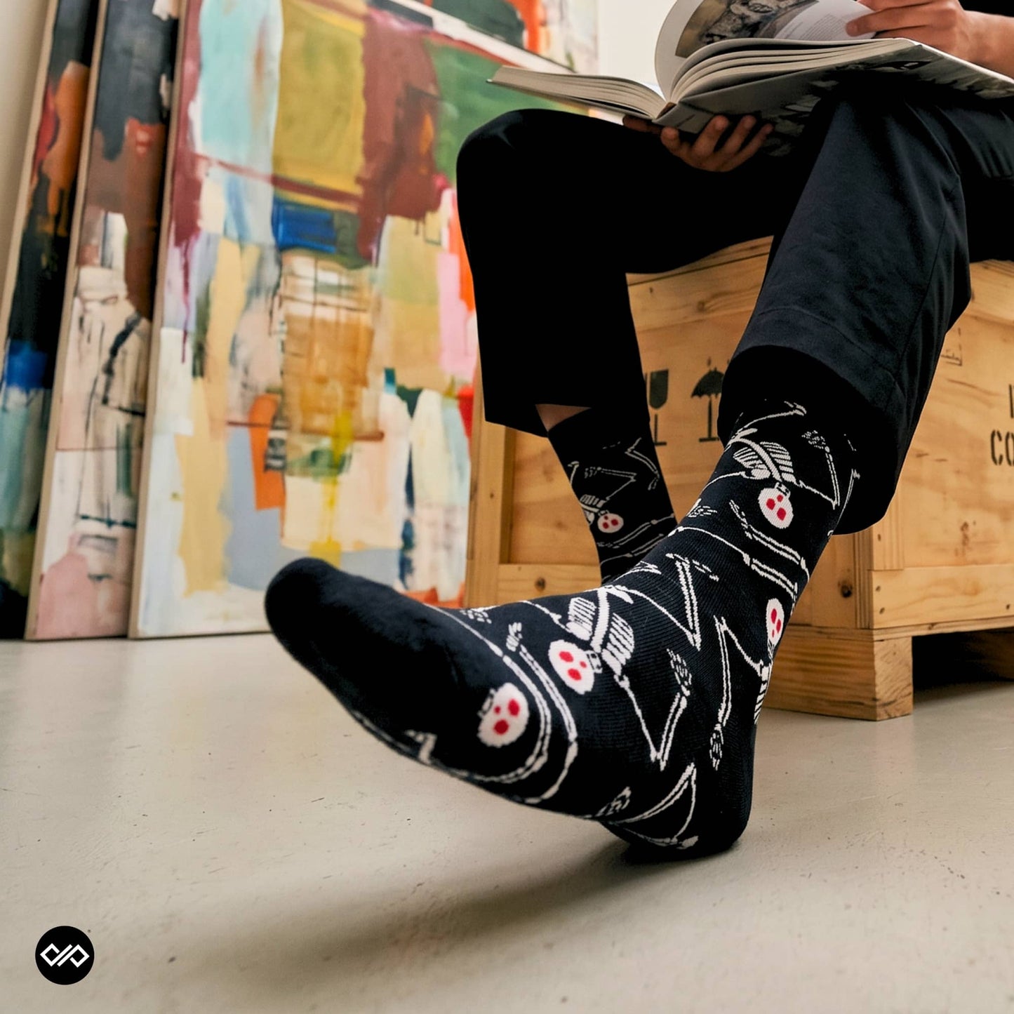 Skeleton crew socks worn with dark trousers in an art studio setting — Dynamocks
