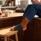 Orange and olive striped crew socks for men styled with dark denim in a modern kitchen — Dynamocks designer socks