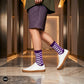 Sublime purple check crew socks styled with purple shorts and white sneakers in modern hallway — Dynamocks