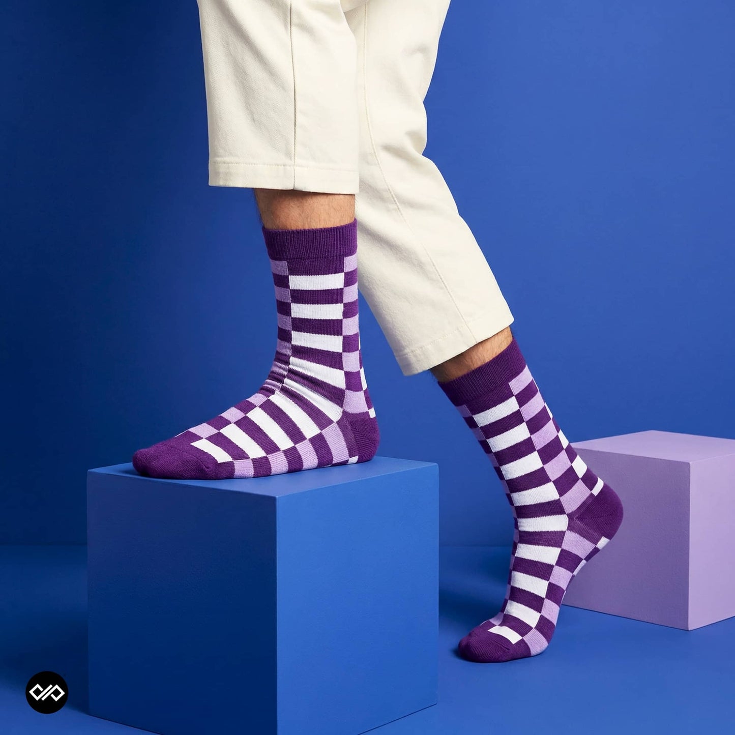 Sublime purple check crew socks for men styled with white trousers on blue studio cubes — Dynamocks India