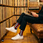 Sublime red check crew socks for men styled with black trousers and white sneakers in a vinyl record store — Dynamocks India