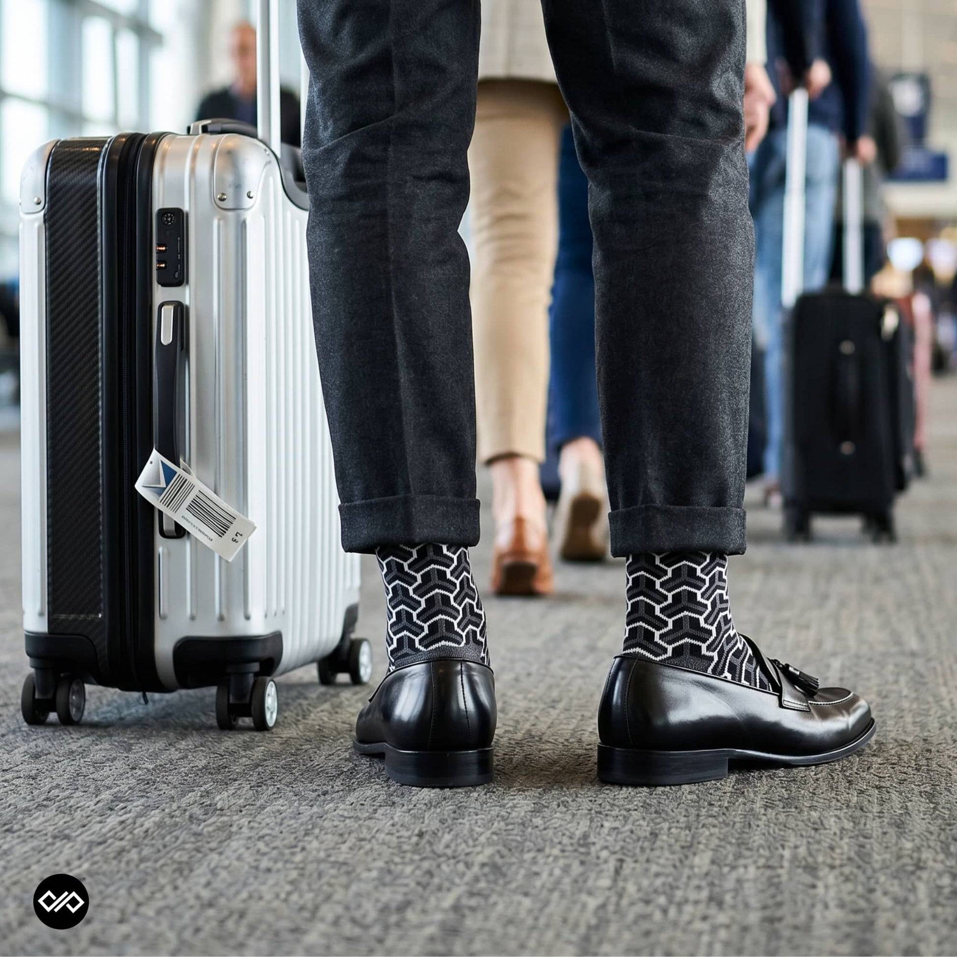 Trios geometric crew socks styled with charcoal trousers and black tassel loafers at an airport terminal — Dynamocks